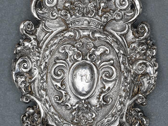 Amulet to Be Hung over the Crib of a Newborn Silver amulet with decorative edges and Hebrew word etched in center.