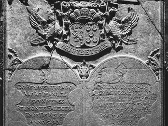 Tombstone with crest on top, and twin columns of text below.