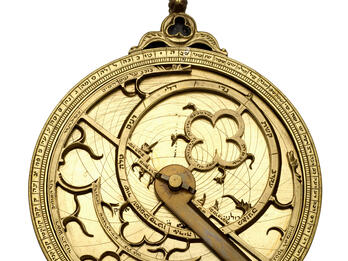 Astrolabe Watch-like device with concentric circles, inner geometric shapes and hands.