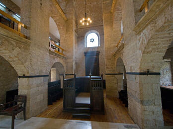 Photograph of room with arched stone doorways and central wooden platform. 