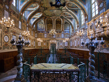 Photograph of room with vaulted ceiling, gilded walls, and pews. 