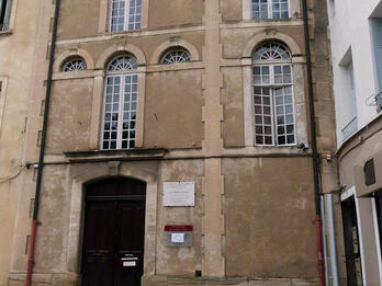 Exterior photograph of building facade with arched windows. 