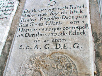 Tombstone with inscription in Hebrew and Portuguese above floral motifs and engraving of hand with an ax reaching out of cloud to chop down tree.