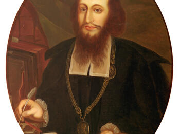 Portrait painting of bearded man wearing medallion holding quill and papers and facing viewer.