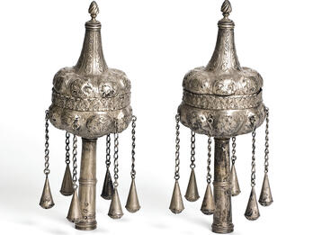 Pair of finials with decoration and chains hanging down. 