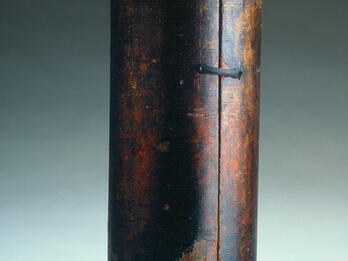 Torah Case Cylindrical case with small ball on top.
