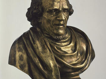 Bust of man on pedestal.