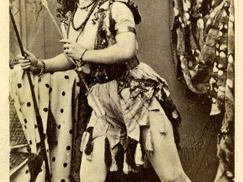 Full body portrait of woman with legs slightly bent and body shifted to one side in an active pose, wearing armor. 