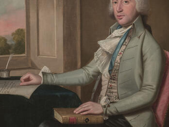 Portrait painting of man seated at desk in front of an open window, facing viewer and holding a book in his lap with his right hand on desk.