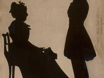 Silhouette portrait of a seated woman and a boy, standing.