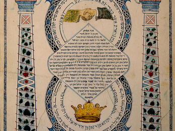 Ketubah Page of Aramaic text featuring two pillars decorated with plant foliage and topped with clocks. Center depicts a crown at the bottom, Hebrew text, and hands clasped at the top.