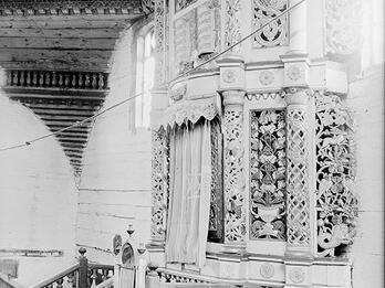 Photograph of interior of building featuring menorah and decorated Torah ark.