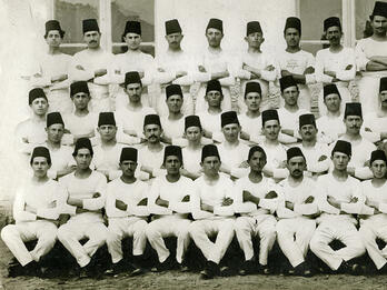 Group portrait of men dressed alike and wearing fezzes.