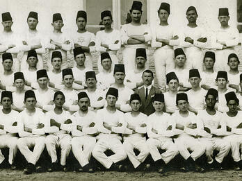 Group portrait of men dressed alike and wearing fezzes.