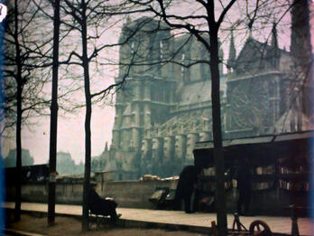 Photograph of a sidewalk and large cathedral looming behind it.