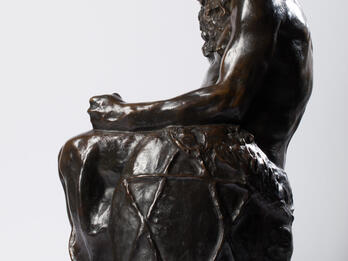 Bronze sculpture of seated figure with beard and Star of David etched onto its side.