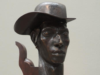 Bust of man wearing a hat.
