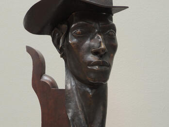 Bust of man wearing a hat.