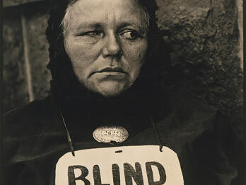Blind Woman Photograph of woman wearing a sign around her neck that reads "BLIND."