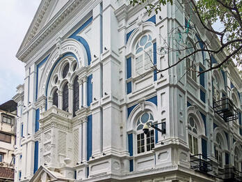 Photograph of building façade with significant decorative trim on window frames and beams.