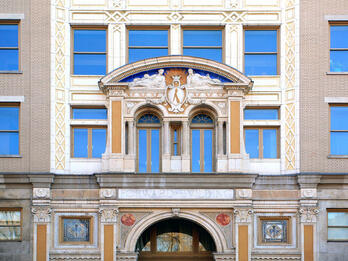 Façade of building with arched entryways and columns with ornate capitals.