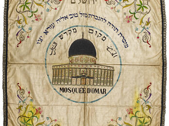 Mazal Tov Eliyahu Ezra Challah Cover Embroided cloth with domed building in center, surrounded by Hebrew and Arabic text, and flowers in each corner.