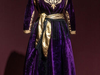 Dress with sash and embroidered neckline and sleeves.