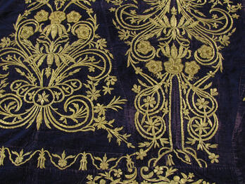 Cloth embroidered with decorative flowers, spirals, and lines.