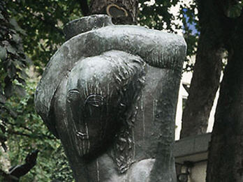 Sculpture of stylized nude woman carrying water over her head.