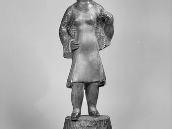 Sculpture of woman wearing dress and hat looking to her left.