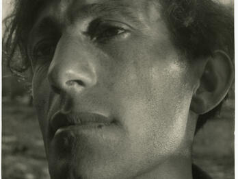 Close-up photograph of man's face. He has no expression and is looking to his right.