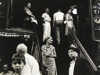 Hester Street Photograph of people standing outside along stairwell and storefronts.