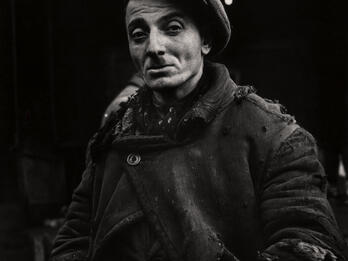 Porter Nat Gutman, Warsaw Photograph of man with mustache and hat wearing torn clothing with hands on hips, looking at camera.