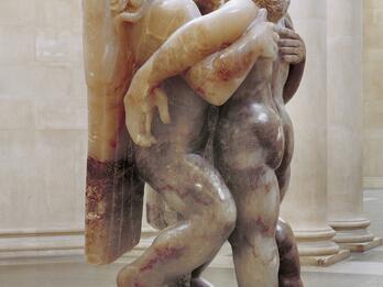 Sculpture depicting angel and man, both upright, with arms around each other.