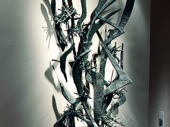 Large-scale abstract sculpture of sharp metal lines and edges installed on wall.