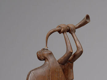 Wood carving of man blowing shofar.