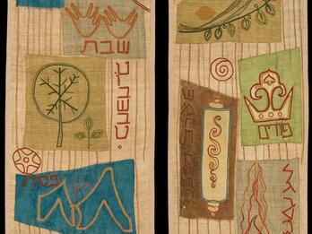 Textile featuring two panels depicting Torah scrolls, Hebrew words, candles, scale, geometric shapes, and floral and plant motifs.