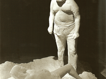 Sculpture of a man standing over a boy lying on his back. 