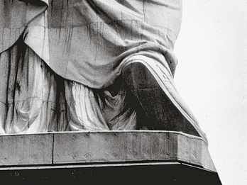 Statue of Liberty Photograph depicting pedestal of large sculpture with people standing around its base.