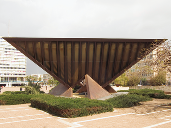 Photograph of inverted pyramid sculpture in the middle of a city square.