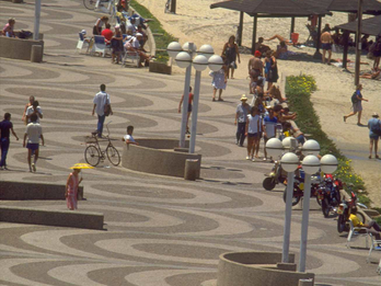 Tel Aviv Promenade, Tel Aviv-Jaffe, Israel Photograph featuring a promenade alongside a beach with people walking and sitting, with several sets of lightposts and circular benches.