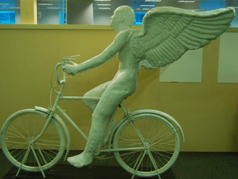 Sculpture of winged figure on bicycle.