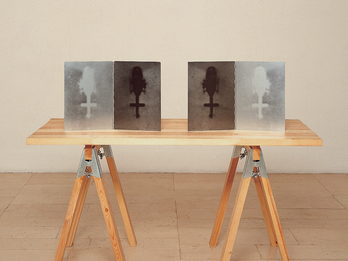 Sawhorse table with four images of a helicopter from a bird's-eye view propped up on it. 