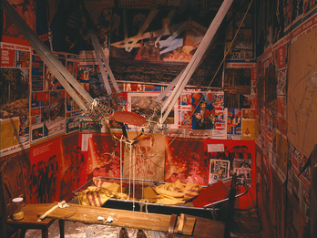The Man Who Flew into Space from His Apartment Installation featuring catapult-like contraption in the middle strung between two walls, a hole in the ceiling, and scientific drawings and posters on the walls.