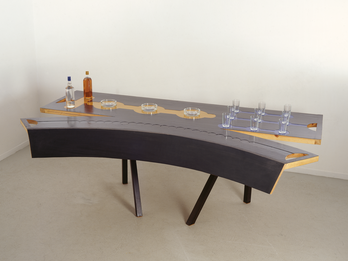 The Table As It Is Sculpture of a cracked table with set of drinking glasses and glass ashtrays on it.