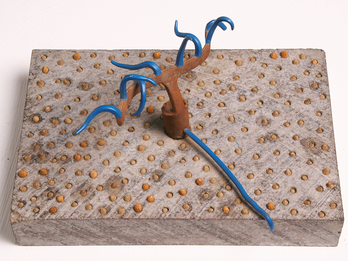 Abstract sculpture featuring iron lines protruding from cement base covered in small circles.