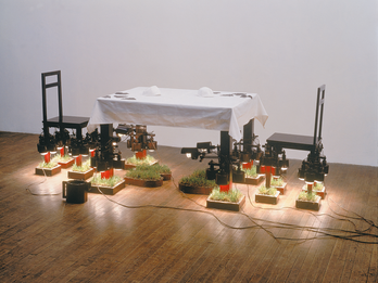 Art installation of table and chairs with individual squares of grass on ground.