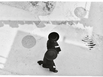 Aerial photograph of two people in hats and suits walking.