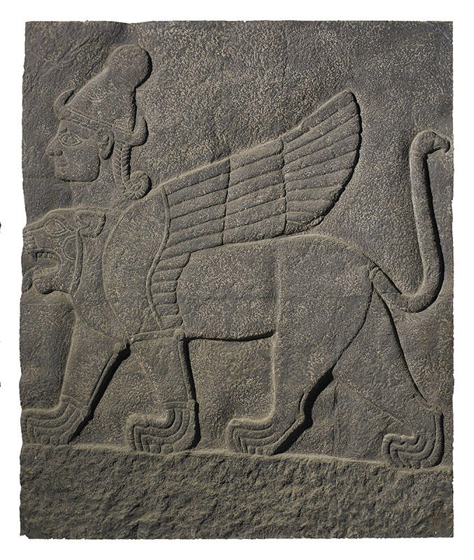 Stone relief of winged lion-like figure with extra head wearing headdress.