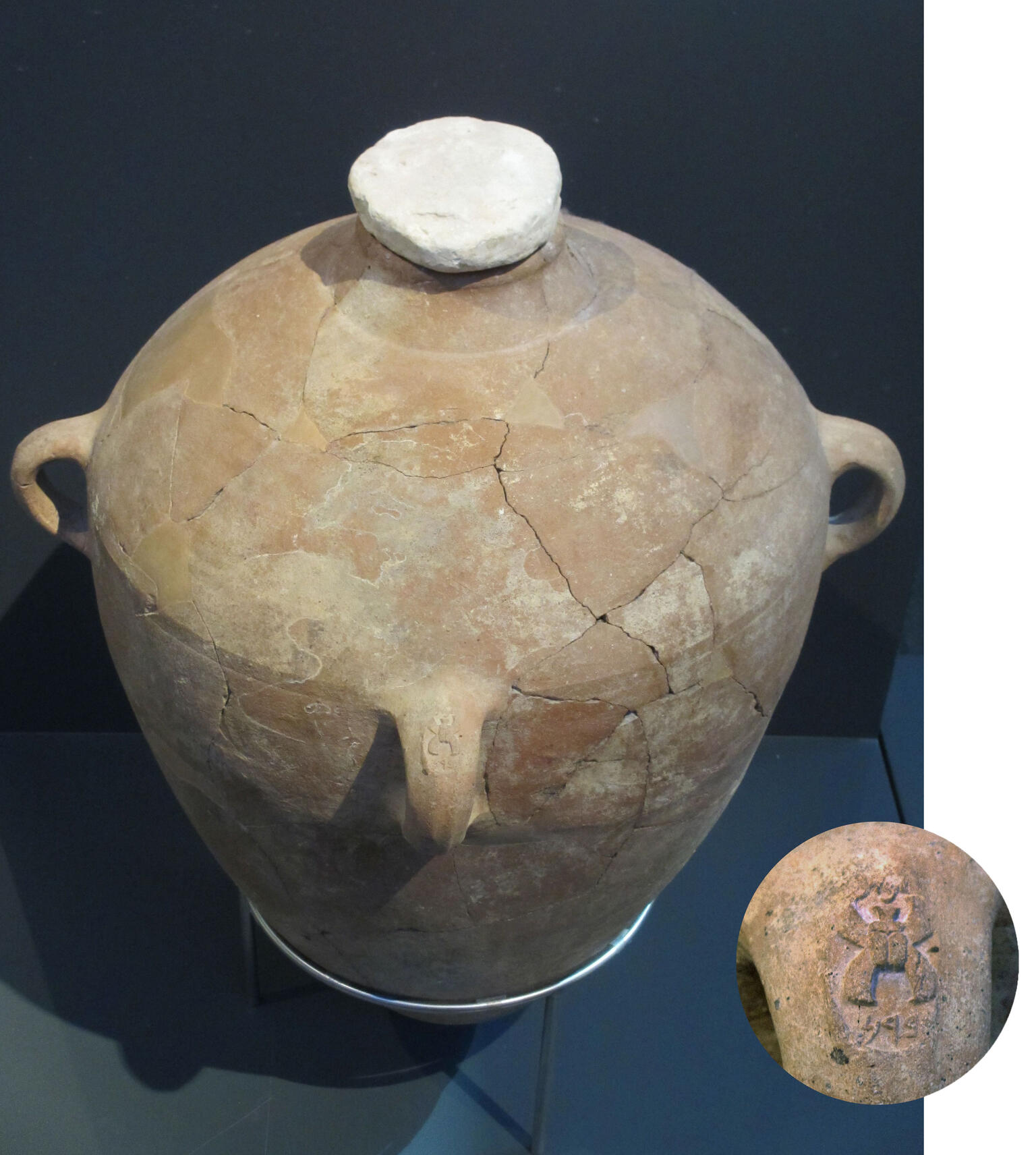 Large clay storage jar with stopper in neck and handle stamped with Hebrew letters.